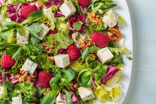 Green salad with slices of blue cheese , raspberries and nuts. photo