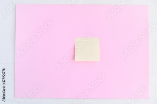 Empty yellow paper note on pink background. Blank Sticky reminder on neutral backdrop. Mockup concept with paper piece on the board. Memory card with empty space for image or text. Memo sticker 