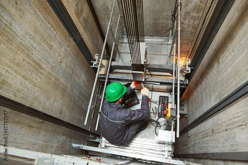 lift machinist repairing elevator in lift shaft photo