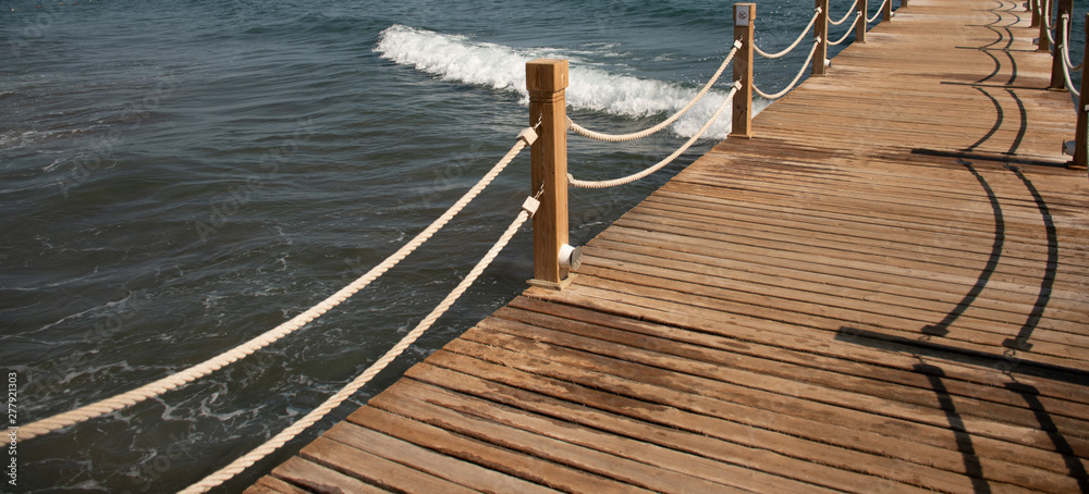 Naklejka premium Scene at Tropical Beach Resort with wooden pier and rope