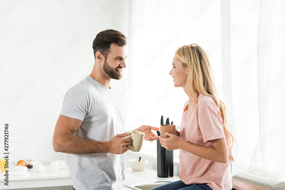 Fototapeta premium beautiful couple with cups of coffee during breakfast at kitchen