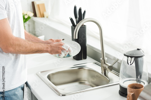 Bild auf Leinwand Cropped view of man washing dishes at kitchen in morning