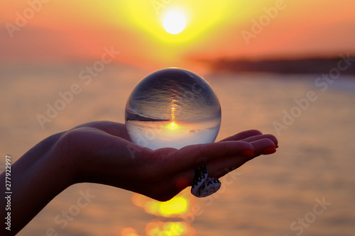 Fototapeta Naklejka Na Ścianę i Meble -  Crystal ball in the palm with an inverted reflection of the sunset on the sea in Turkey in Kizilagac.