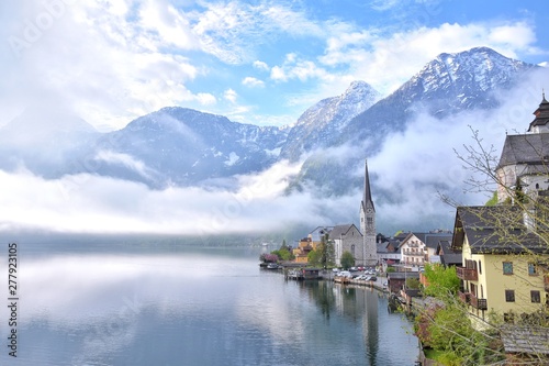 Amazing Hallstatt village with beautiful lake and alps mountains on background. Unesco heritage. Austria landmark with historic cathedral and wooden houses on the lake. Romantic view 