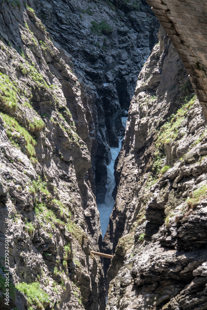 View of a wild river in the Viamala gorge with old historic stone bridge in the Swiss Alps