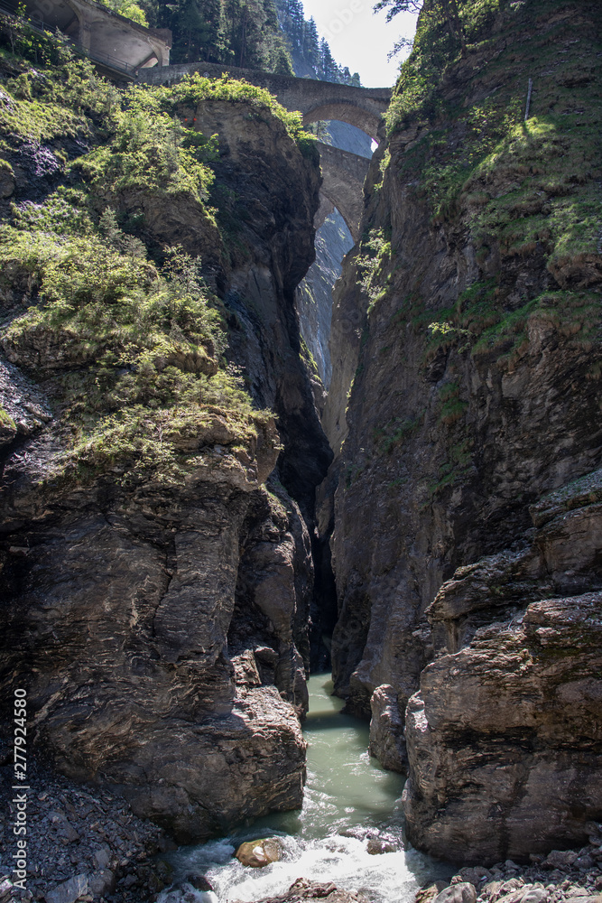 View of a wild river in the Viamala gorge with old historic stone bridge in the Swiss Alps