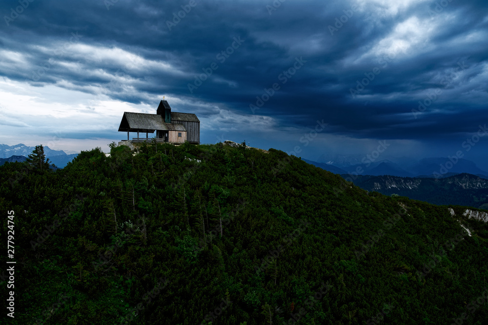 Dramatic mountain sky with storm clouds and mountain chapel Tabor on Hochfelln mountain in Bavaria near Chiemse 