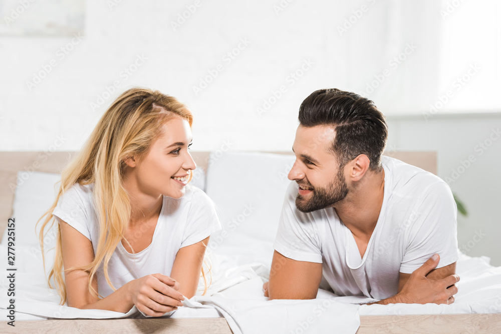 beautiful smiling couple resting on bed at home beautiful smiling couple resting on bed at home