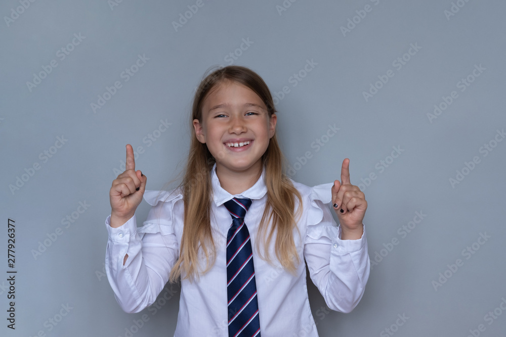 Young schoolchild pointing up portrait. Preteen schoolgirl looking at camera, gesturing at ceiling. Happy girl, kid in school uniform. Back to school, joyful, cheerful pupil, student ready for class Young schoolchild pointing up portrait. Preteen schoolgirl looking at camera, gesturing at ceiling. Happy girl, kid in school uniform. Back to school, joyful, cheerful pupil, student ready for class