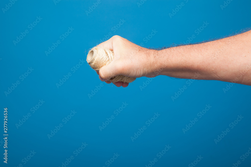 Rollo de cordel o de cuerda sujeto por la mano de una persona, mano derecha sujeta rollo de cordel rústico. Puño cerrado sujetando rollo de cordel Rollo de cordel o de cuerda sujeto por la mano de una persona, mano derecha sujeta rollo de cordel rústico. Puño cerrado sujetando rollo de cordel