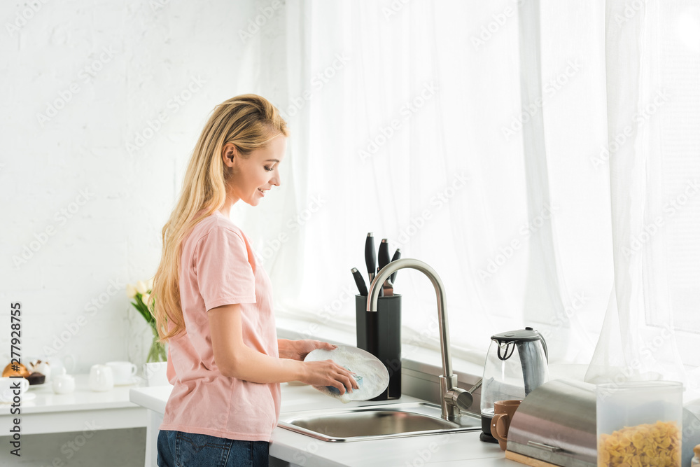 beautiful woman washing dishes at kitchen in morning