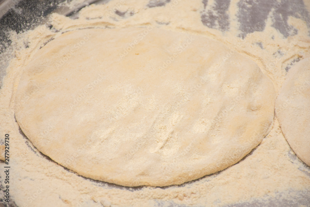 Dough and flour on a wooden board close-up