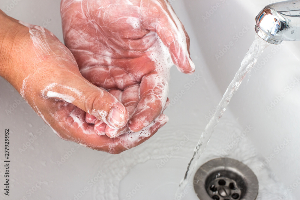 The hands of a man who washes his hands with soap dispenser.