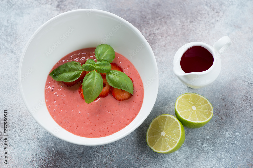 White bowl with cold strawberry cream-soup, elevated view over light-grey stone background White bowl with cold strawberry cream-soup, elevated view over light-grey stone background