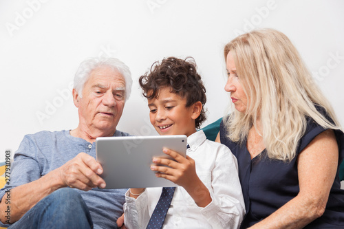 GRANDS PARENTS AVEC LEUR PETIT FILS REGARDANT UNE TABLETTE
