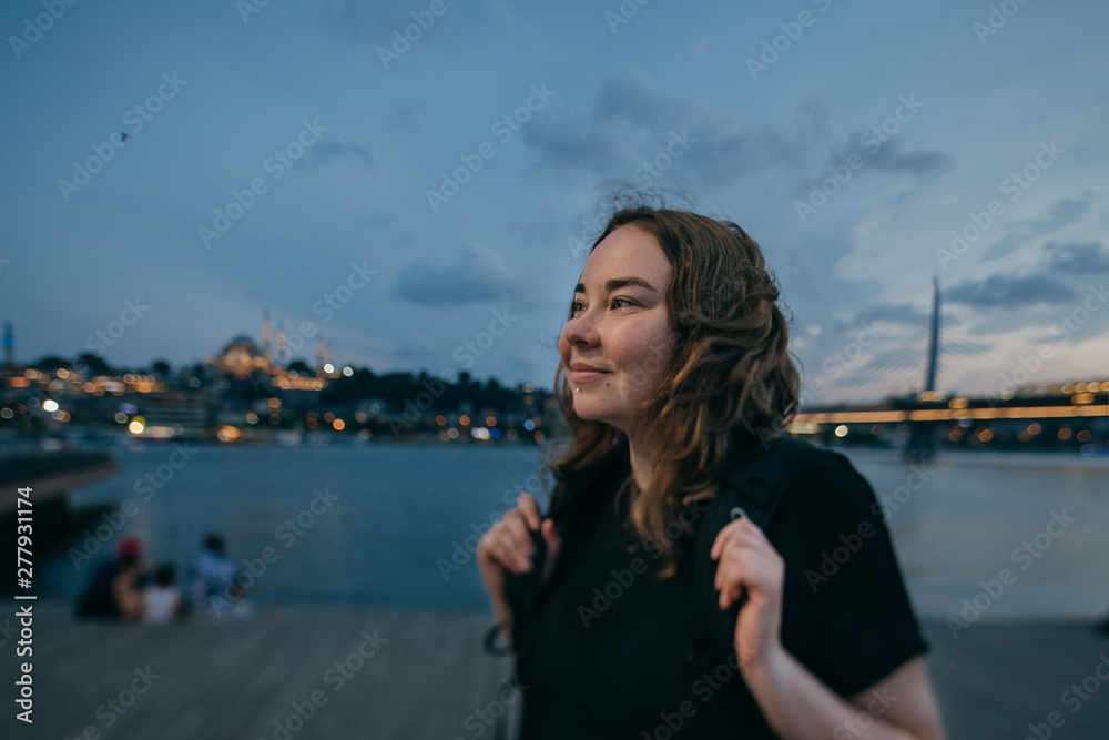 The girl at sunset on the waterfront on the background of the city