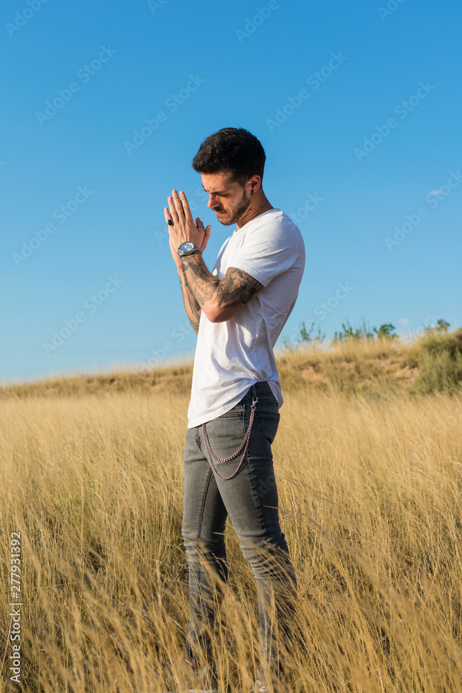 Attractive man with tattoos on his arms in a meadow Attractive man with tattoos on his arms in a meadow