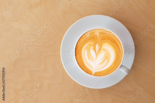 a cup of hot latte coffee on wooden table in coffee shop