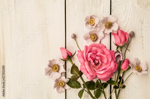 flowers of a gentle pink rose, leaves on a light wooden background
