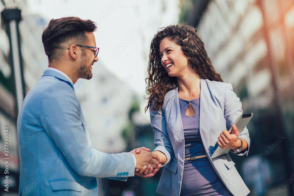 Smiling business colleagues greeting each other outdoors - obrazy, fototapety, plakaty 