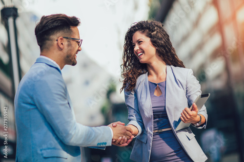 Smiling business colleagues greeting each other outdoors photo