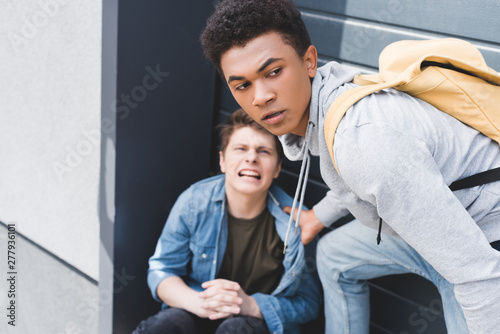 selective focus of african american boy in hoodie and jeans bulling screaming and scared boy