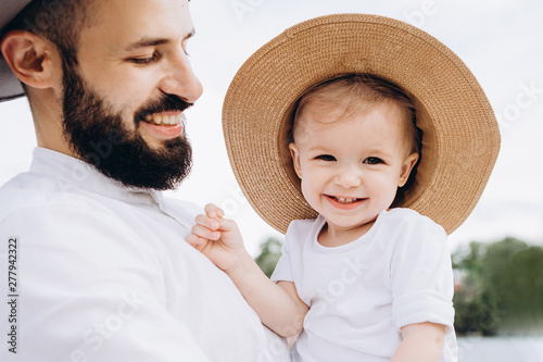 Family portrait. Father with daughter: Stylish bearded man in white shirt holding his daughter on his hands, they smile and rejoice. Copy space