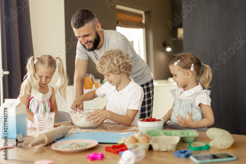 Delighted positive man cooking with his children