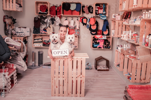Fotografie Dark-haired woman smiling while opening shop for pets