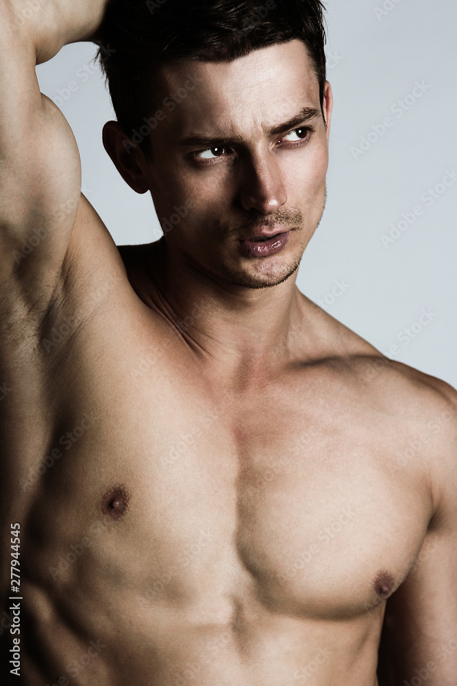 Male beauty concept. Portrait of shirtless handsome young man with stylish haircut posing over gray background. Perfect hair & skin. Close up. Studio shot Male beauty concept. Portrait of shirtless handsome young man with stylish haircut posing over gray background. Perfect hair & skin. Close up. Studio shot