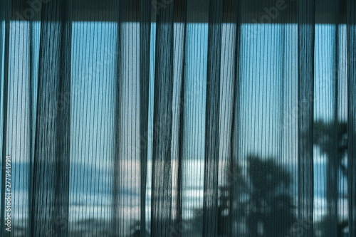 Mesh curtain drawn across window of hotel room overlooking the ocean