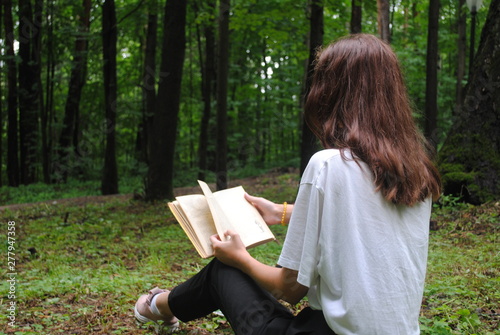 young woman reading a book in park