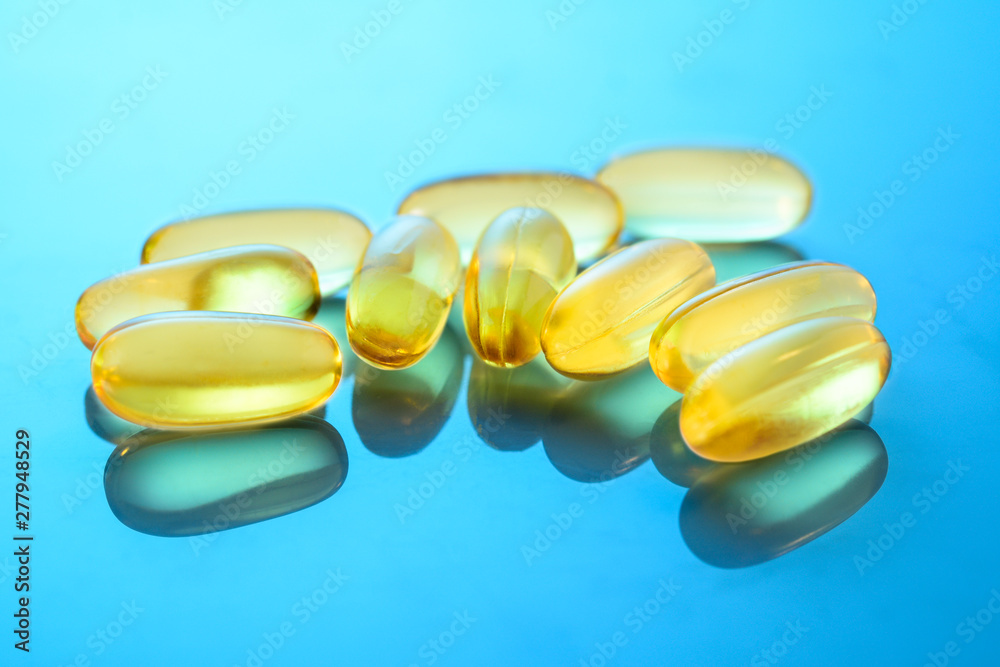Omega 3 capsules on the gloss surface with reflections. Some fish oil capsules, closeup macro. Omega 3 capsules on the gloss surface with reflections. Some fish oil capsules, closeup macro.