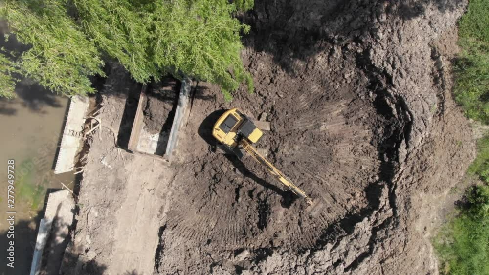 Excavator digging soil and loading dump truck tipper at excavation site aerial static Excavator digging soil and loading dump truck tipper at excavation site aerial static