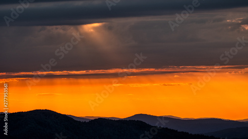 Fototapeta Naklejka Na Ścianę i Meble -  A wonderful sunset in the mountains. Orange sky and dark silhouettes of mountains. Carpathian Mountains landscape. Bieszczady. Poland