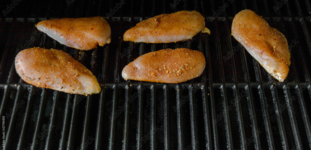 Seasoned raw chicken breasts grilling on a barbeque Seasoned raw chicken breasts grilling on a barbeque
