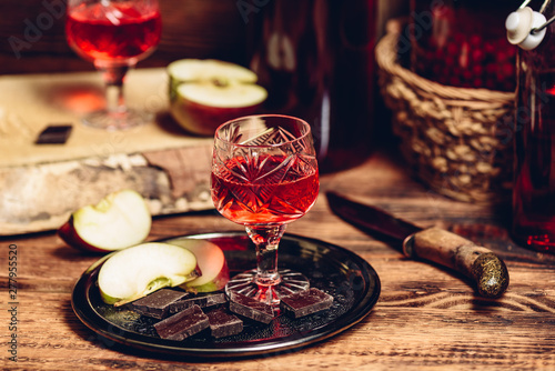 Glass of homemade currant nalivka and chocolate with apple