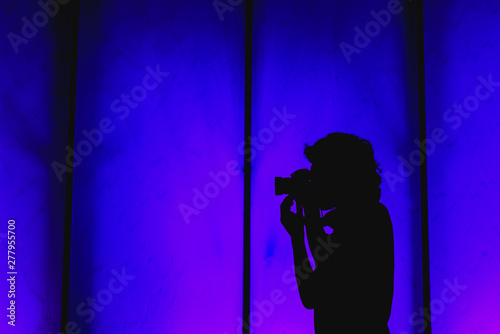Silhouette of a profile photographer on a wall background.