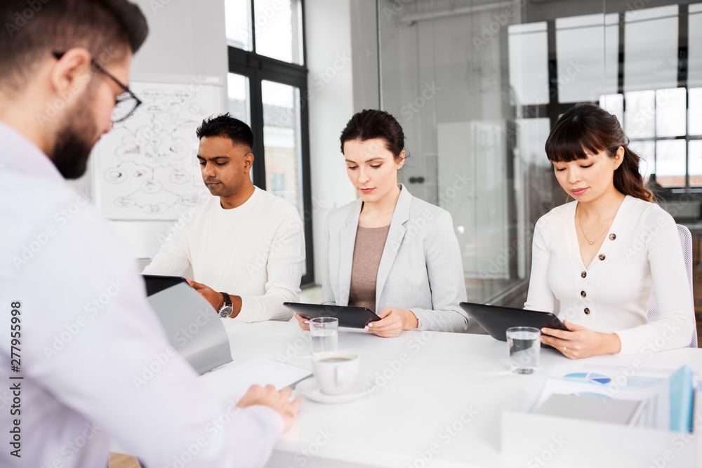 new job, hiring and employment concept - international team of recruiters with tablet computers having interview with male employee at office new job, hiring and employment concept - international team of recruiters with tablet computers having interview with male employee at office