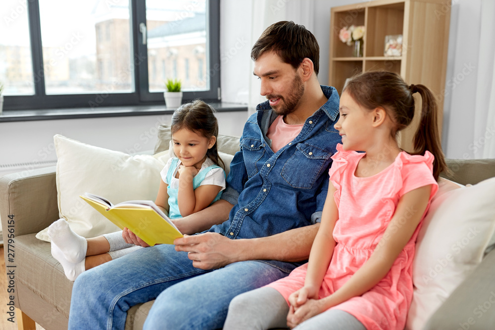 family, leisure and people concept - happy father with daughters reading book at home