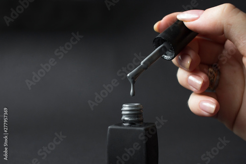 gray shellac nail polish dripping on black background with copy space photo