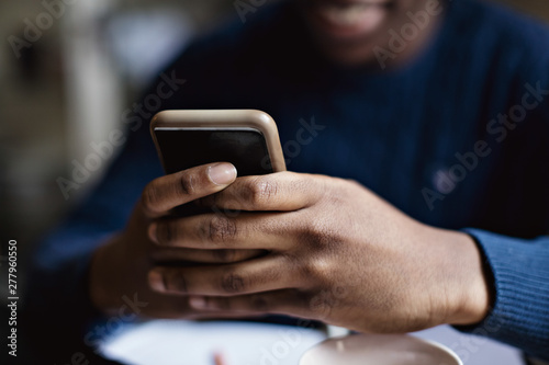 Social media addicted teenage boy using smart phone while studying at home