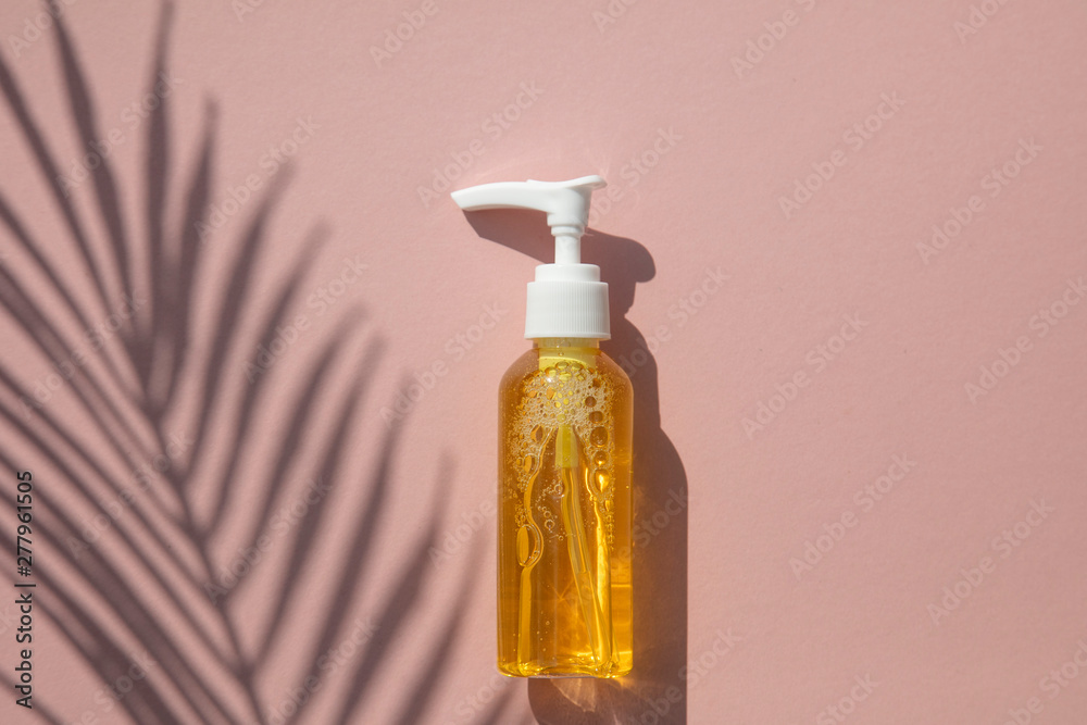 Natural cosmetic oil in a clear bottle with tropical leaf and shadow Natural cosmetic oil in a clear bottle with tropical leaf and shadow