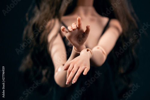 Hinged doll on a black background. Beautiful female hands closeup. photo