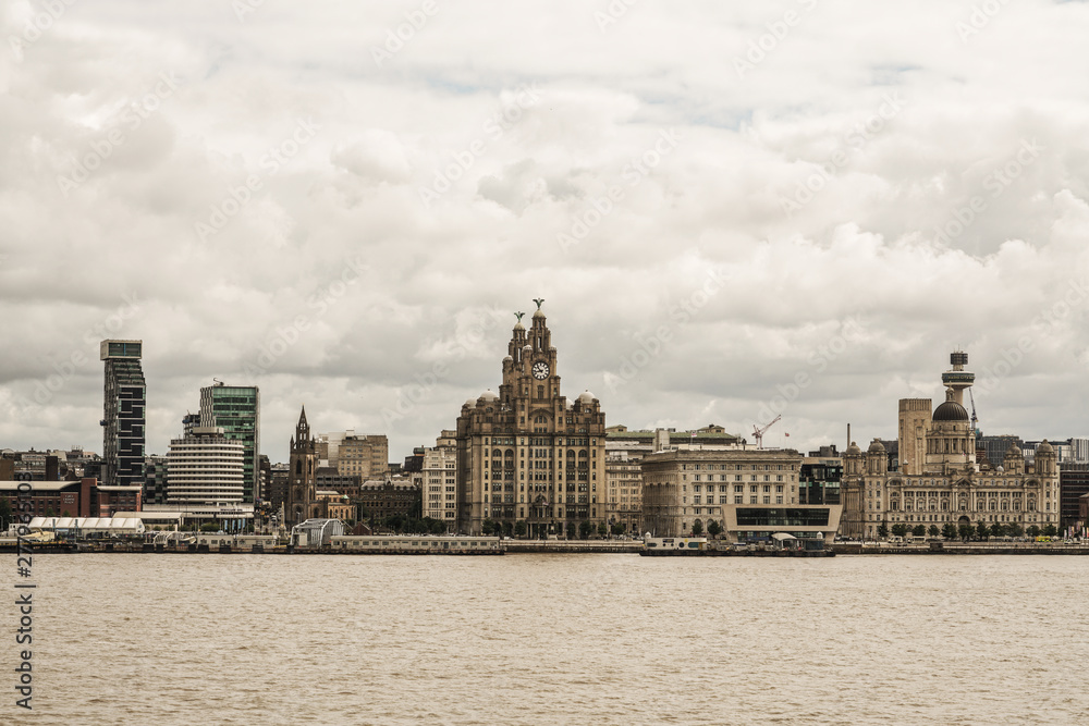Liverpool seafront view from ferry in a summer cloudy day with the royal liver building imposing 