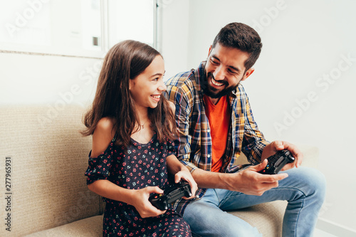 Smiling father and daughter playing video game at home photo