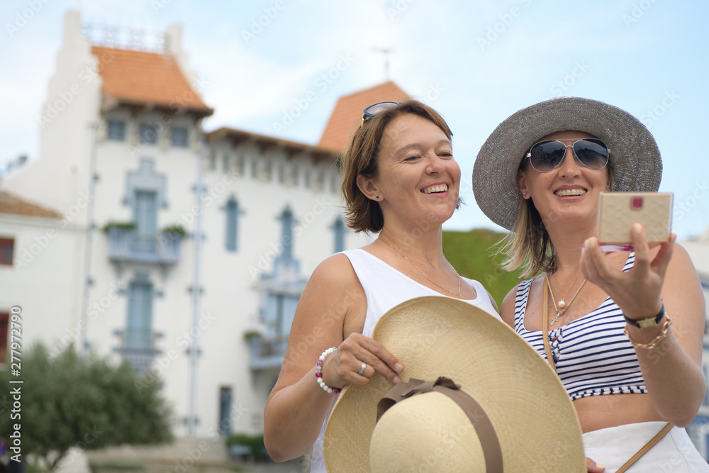 Fototapeta premium Two happy women looking at the mirror in a mediterranean village