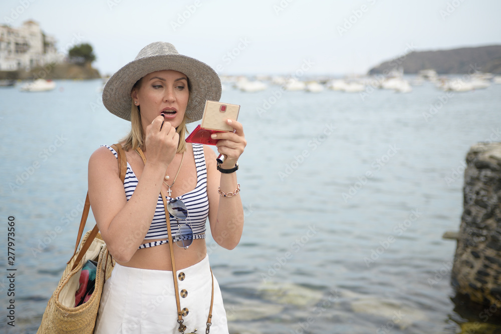 Happy woman using her lipstick over seaside promenade
