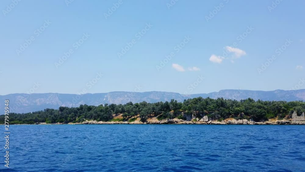A tracking shot of idyllic Aegean islands in the summer, from Gulf of Gokova. Stone ruins from Roman times can also be seen on the island. Shot and presented at 60 fps. A tracking shot of idyllic Aegean islands in the summer, from Gulf of Gokova. Stone ruins from Roman times can also be seen on the island. Shot and presented at 60 fps.