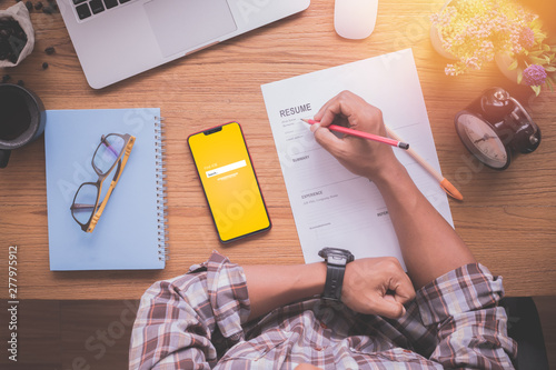 wood table with businessman filling resume information.